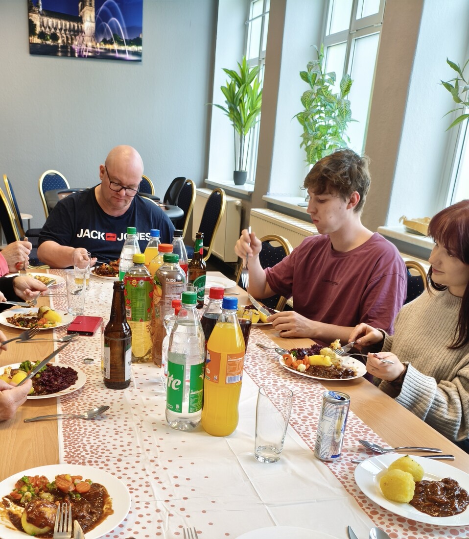 Vier Personen genießen ein Essen an einem gedeckten Tisch mit Getränken.