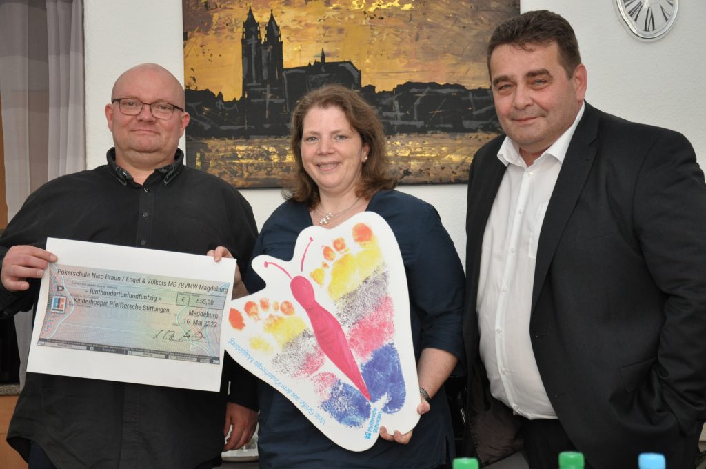 Drei Personen lächeln, halten Scheck und bunten Schmetterling, Hintergrund gemaltes Bild.